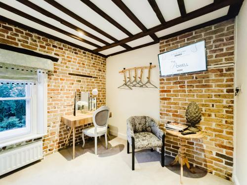 a room with a brick wall and a desk and chair at The Powell Birchington, Boutique Rooms in Birchington