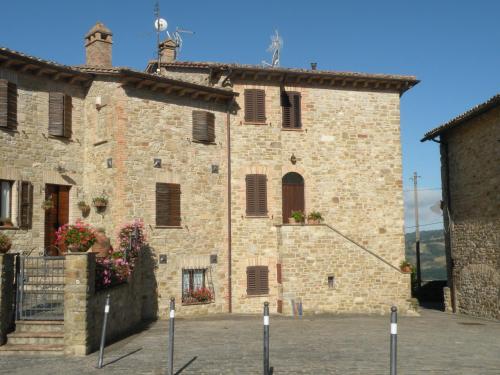 a large stone building with windows and flowers on it at Il Nido nel Borgo in Valfabbrica