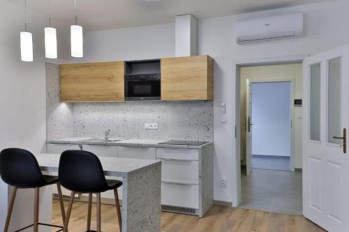 a kitchen with two black chairs and a counter at Apartmány U Bílé labutě in Olomouc
