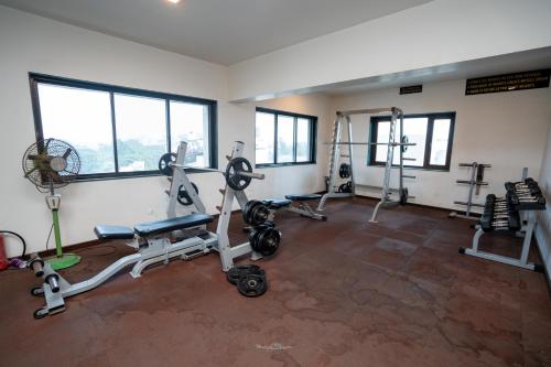 a gym with treadmills and machines in a room with windows at Hotel Vrishali Executive in Kolhapur