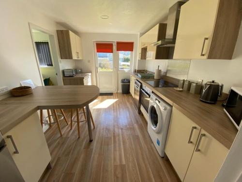a kitchen with a table and a washing machine at Summerdale Kirkwall in Orkney