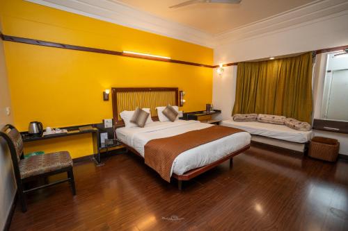 a bedroom with a large bed and a yellow wall at Hotel Vrishali Executive in Kolhapur