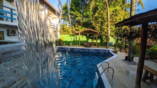 a swimming pool in a backyard with a water fountain at Hotel Estalagem Porto Seguro in Porto Seguro