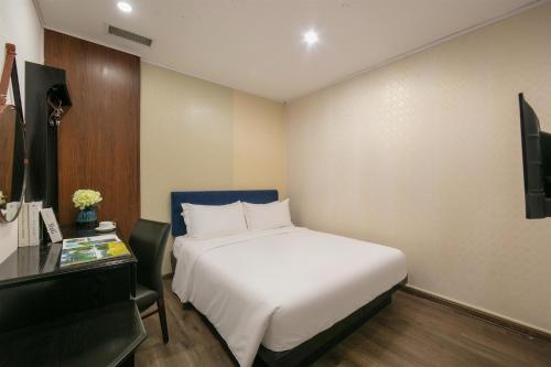 a bedroom with a bed and a desk and a television at Hanoi Traveller House in Hanoi