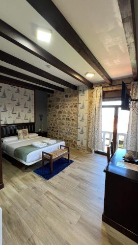 a bedroom with a large bed and a stone wall at Rústico Prado da Viña in Finisterre