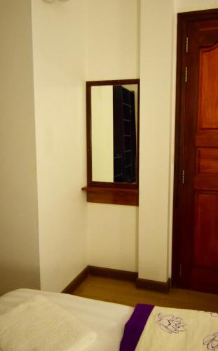 a room with a bed and a mirror and a door at Arianna Dhangethi in Dhangethi