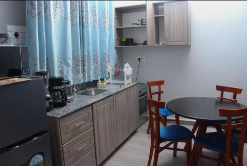 a kitchen with a table and chairs and a sink at HES Bulindo in Nsasa