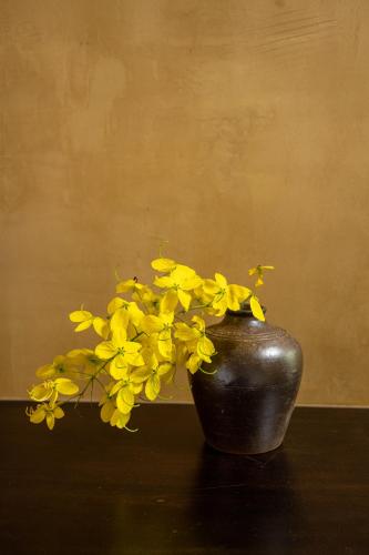 a black vase filled with yellow flowers on a table at Amazing Ninh Binh Garden in Xuân Sơn