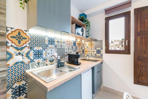 Una cocina con fregadero y pared de azulejos. en Reyes Albaicín, en Granada