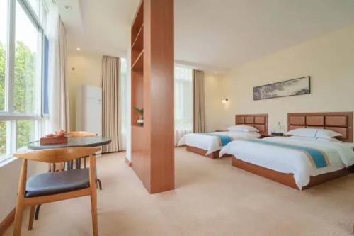 une chambre avec deux lits, une table et un bureau dans l'établissement GANGZHOU BENZYOO B&B（ Baishuizhai Skov River）, à Huangshadang