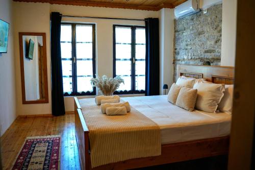 a bedroom with a large bed with two windows at Porta7 Hotel in Gjirokastër