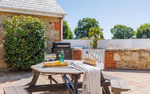 a picnic table with two wine glasses and a grill at Rookley Farm Lodge Charming Manor Pool House with Heated Pool, Tennis Court & Gardens - Isle of Wight Rural Countryside Escape in Rookley