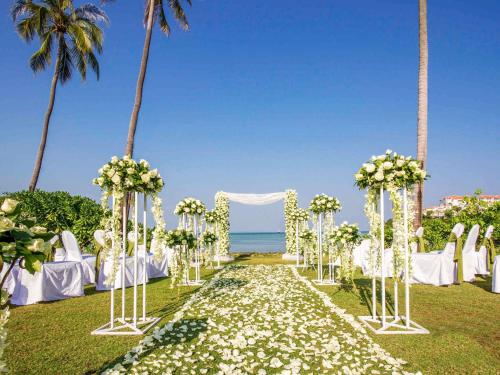 a wedding ceremony at the beach with white flowers at Pullman Phuket Panwa Beach Resort in Panwa Beach