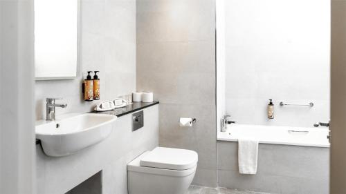 a white bathroom with a toilet and a sink at Mount Wolseley Hotel Spa & Golf Resort in Tullow