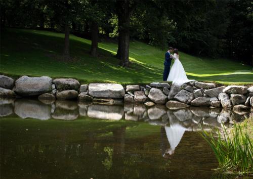 a bride and groom standing next to a pond at Mount Wolseley Hotel Spa & Golf Resort in Tullow