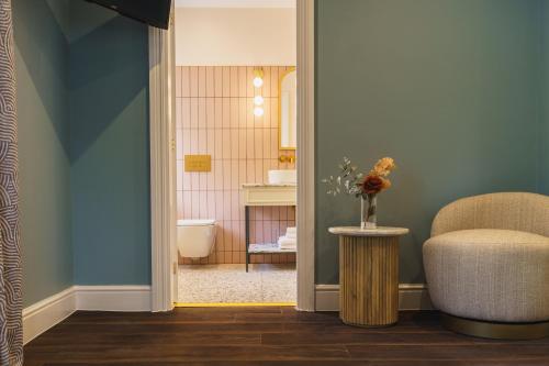 a bathroom with a toilet and a chair in a room at Grange Hotel in Grange Over Sands
