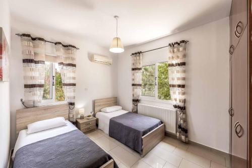 a bedroom with two beds and two windows at Villa Orange Tree in Lachi