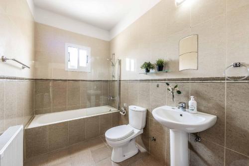 a bathroom with a toilet and a sink and a tub at Villa Orange Tree in Lachi