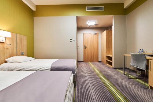 a hotel room with two beds and a desk at Hotel Radocza Park Business in Radocza