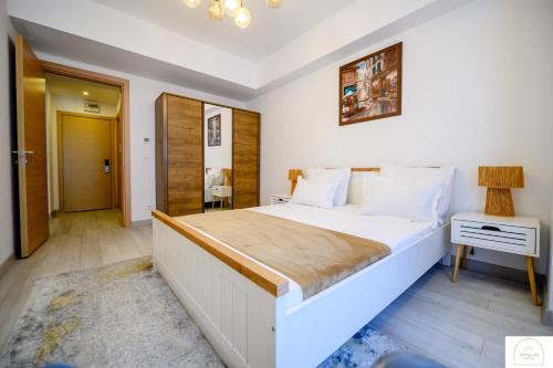 a bedroom with a large white bed and a table at YamaLuxe Luxury Apartments - București in Bucharest