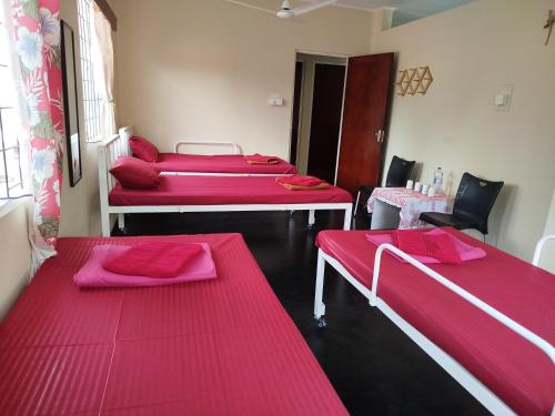 three beds in a room with pink sheets at Holy Spirit Mission Camps in Mount Lavinia