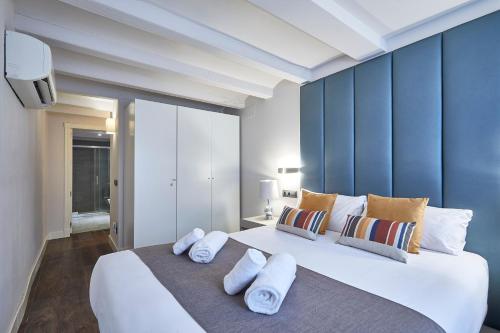a bedroom with a large white bed with blue walls at BBarcelona Rogent Flats in Barcelona