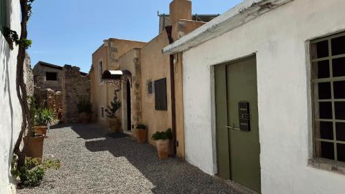 an alley with a green door and some buildings at Santa Veneranda Suites "by Checkin" in Ayía Paraskeví