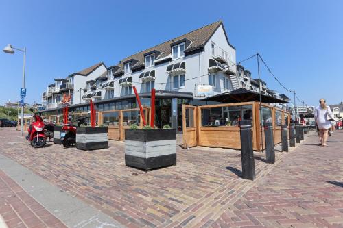 a building on a street with a motorcycle parked in front at Hotel De Boei in Egmond aan Zee