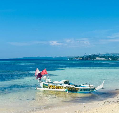 a boat sitting on the beach with an umbrella at Cockatoo Room Rentals Siquijor in Siquijor