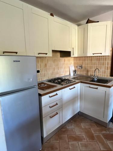 a kitchen with white cabinets and a white refrigerator at Maggiolino al mare in Cavo