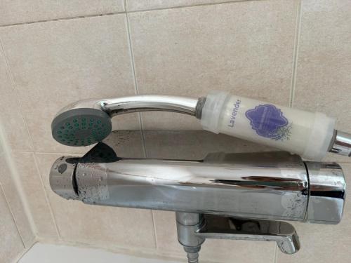 a shower head with a bottle sitting on a holder at Villa con Piscina climatizada in Sanlúcar de Barrameda
