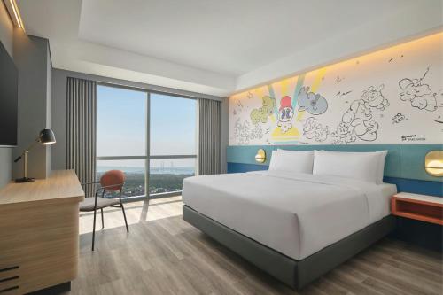 a bedroom with a bed and a desk and a window at Aloft Surabaya Pakuwon City in Surabaya