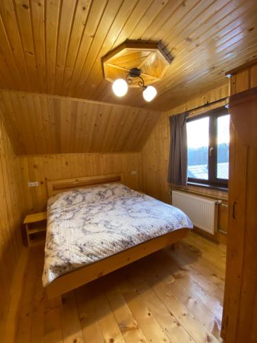 マイコリチンにあるHutsulka Houseの木製の部屋にベッド1台が備わるベッドルーム1室があります。
