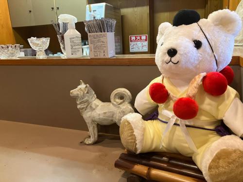 a teddy bear sitting on a table next to a statue at Chikurinin Gunpoen in Yoshino