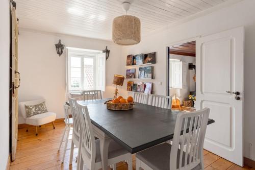 a dining room with a black table and white chairs at GuestReady - Exceptional house near Colares in Colares