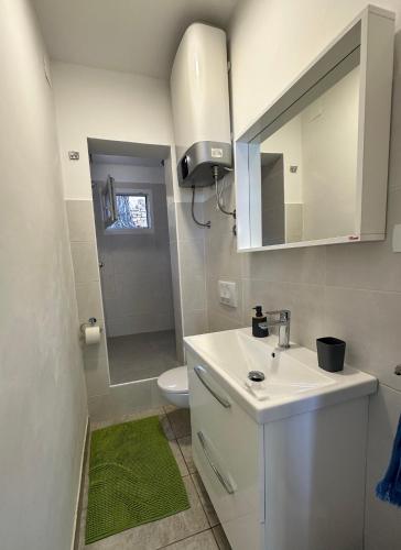 a white bathroom with a sink and a toilet at House Neli in Srednje Selo na Šolti