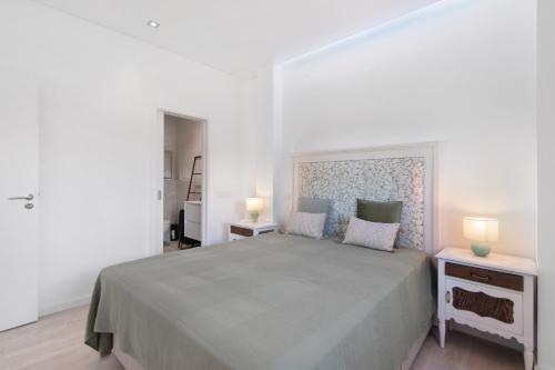 een witte slaapkamer met een groot bed en 2 lampen bij V3 Atlantida Farm in Quelfes