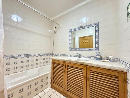 a bathroom with a sink and a tub and a mirror at Monte Gordo Vila Verde by Homing in Castro Marim
