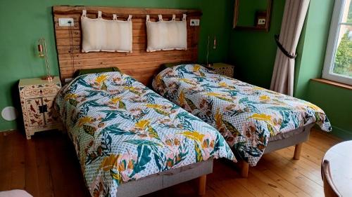 2 letti in una camera da letto con pareti verdi di La Maison de 1868 a Vendeuvre