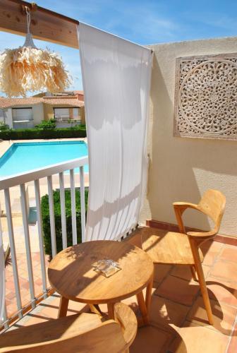 a balcony with a table and a chair and a pool at CAPAO Beach Hôtel in Cap d'Agde