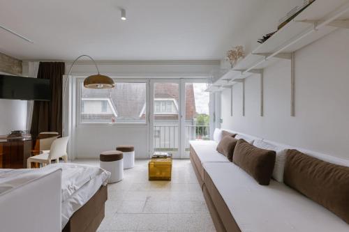 a white living room with a couch and a table at Huswell Studio 14 in Knokke-Heist