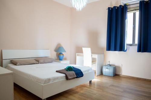 a bedroom with a white bed with blue curtains at Golden Stay - 4BR Stylish Apartment for Group in Tal-Ħriereb