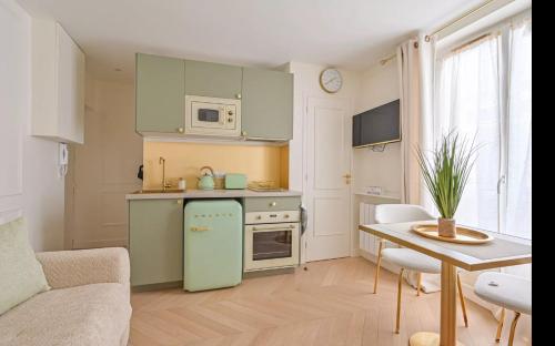 Il comprend une cuisine équipée d'un réfrigérateur vert et d'une table. dans l'établissement Chez Lucette Studio 17e Paris, à Paris