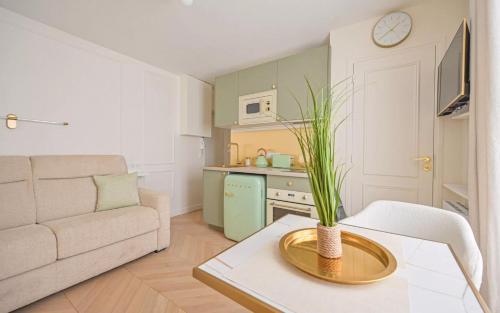 un salon avec un canapé et une table avec une plante dans l'établissement Chez Lucette Studio 17e Paris, à Paris