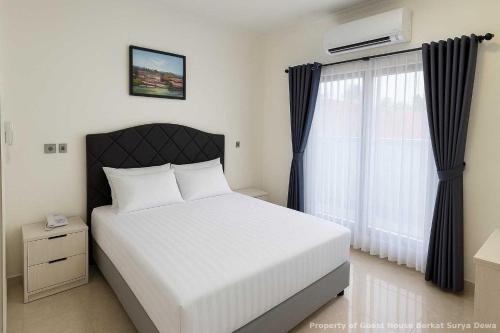 a bedroom with a white bed and a window at Berkat Surya Dewa Guest House in Benuaanyar