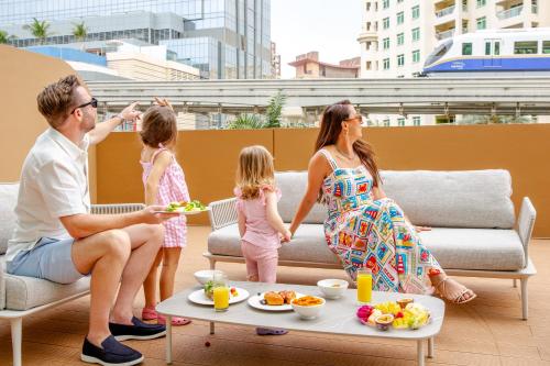 a family sitting on a couch eating food at Cheval Maison - The Palm in Dubai