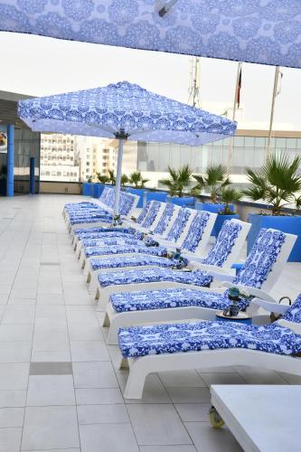 a row of blue and white chairs with an umbrella at Symphony Style Hotel Kuwait in Kuwait