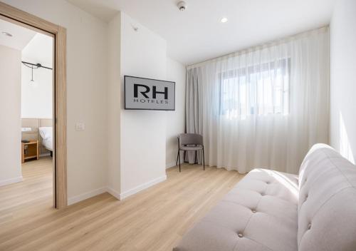 a white living room with a white couch and a mirror at Hotel RH Arena - Todo Incluido in Gandía