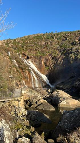 a waterfall on the side of a mountain with rocks at Rústico Prado da Viña in Finisterre