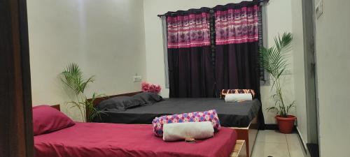 two beds in a room with purple curtains at ADH Amilia Nest in Mysore